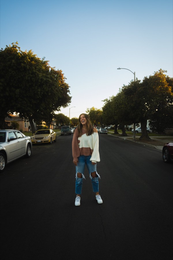 A woman standing in the middle of a suburban street at dusk