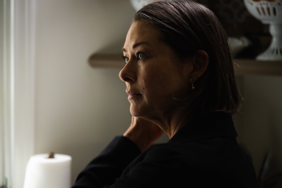 A woman in profile against a pale wall, lit from the side for a filmed interview