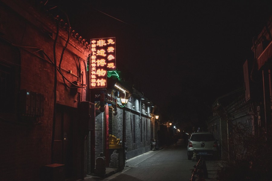 A narrow street at night lit by neon signs