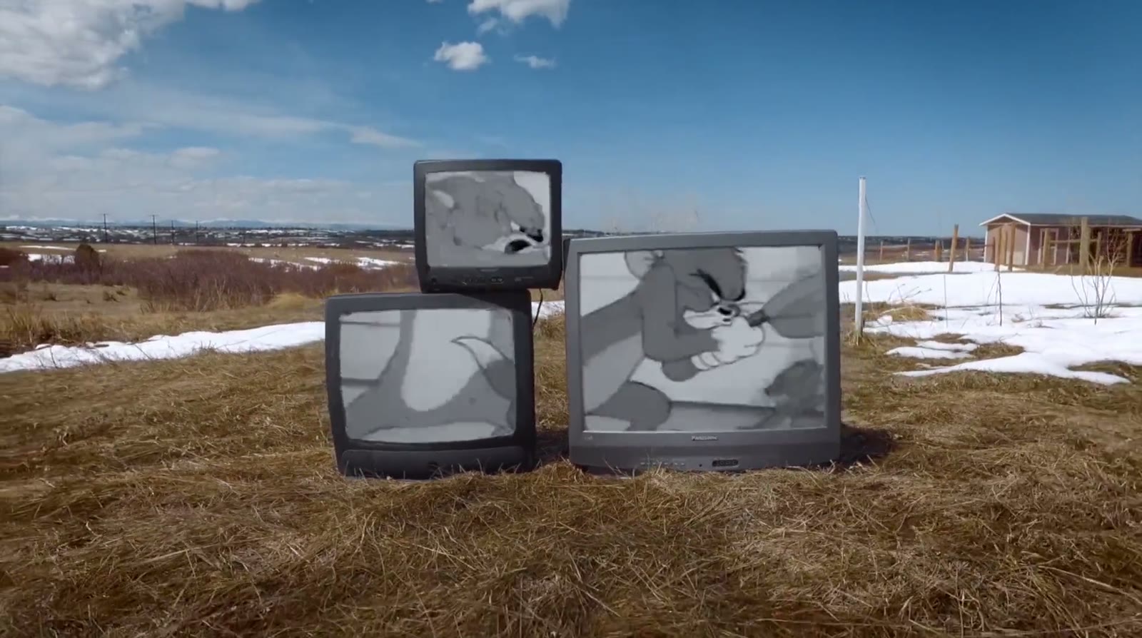 Three old televisions standing in a snowy field